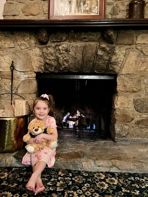 A young girl sits by an in-room fire place at UCLA Lake Arrowhead Lodge.