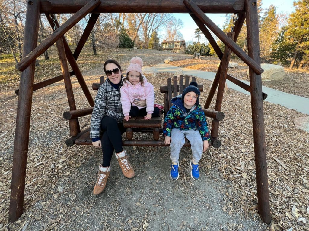 A mom and her two kids enjoy a large swing at UCLA Lake Arrowhead Lodge.