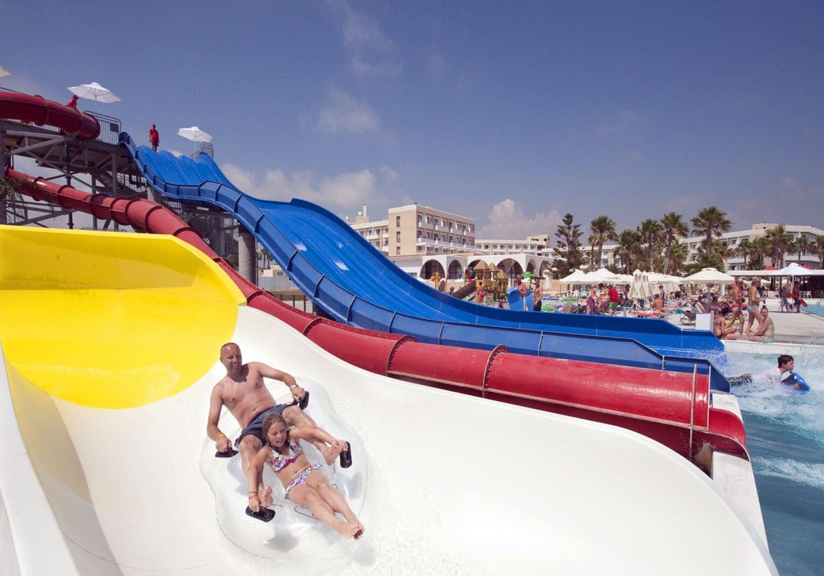 A father and daughter ride down a water slide on a tube at Louis Phaethon Beach Resort.