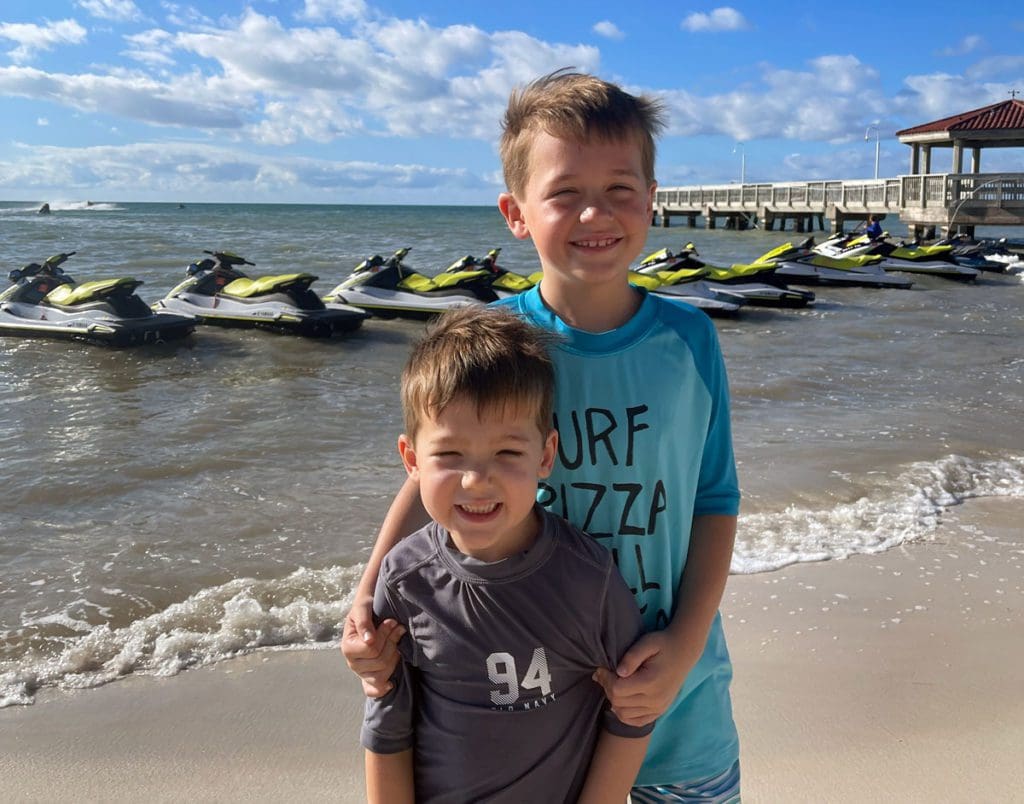 Two young boys stand together on the beach in Key West.