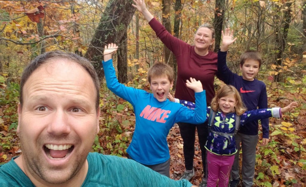 A family of five excitedly cheers while hiking together near Asheville.