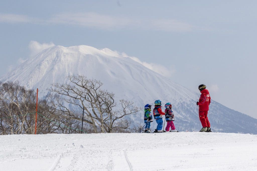 A ski instructor works with three young skiers at Niseko United.
