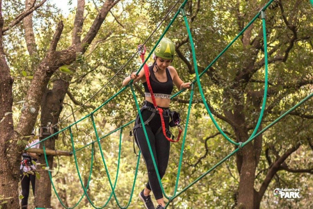 A teenage girl makes her way across a ropes course at Parco Avventura Ciuchino Birichino, one of the best things to do in Puglia with kids.