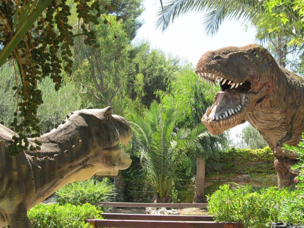 Two animatronic dinosaurs stand opposite each other prepared to battle.