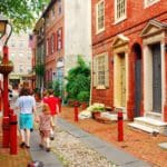 A family of three walks down a historic street in Philadelphia together.