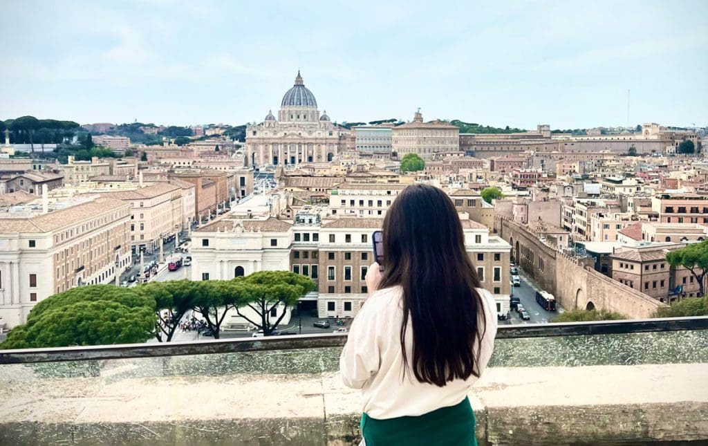 A young girl takes a picture of the Vatican while in Rome with her family.