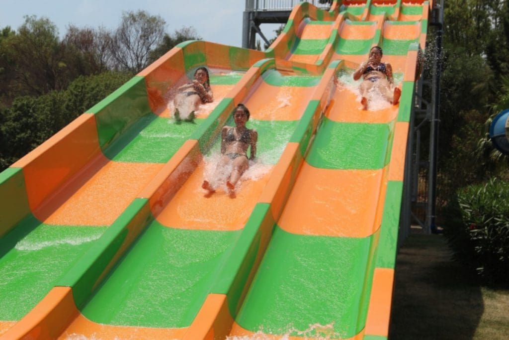 Three kids zoom down water slides at Splash Parco Acquatico.