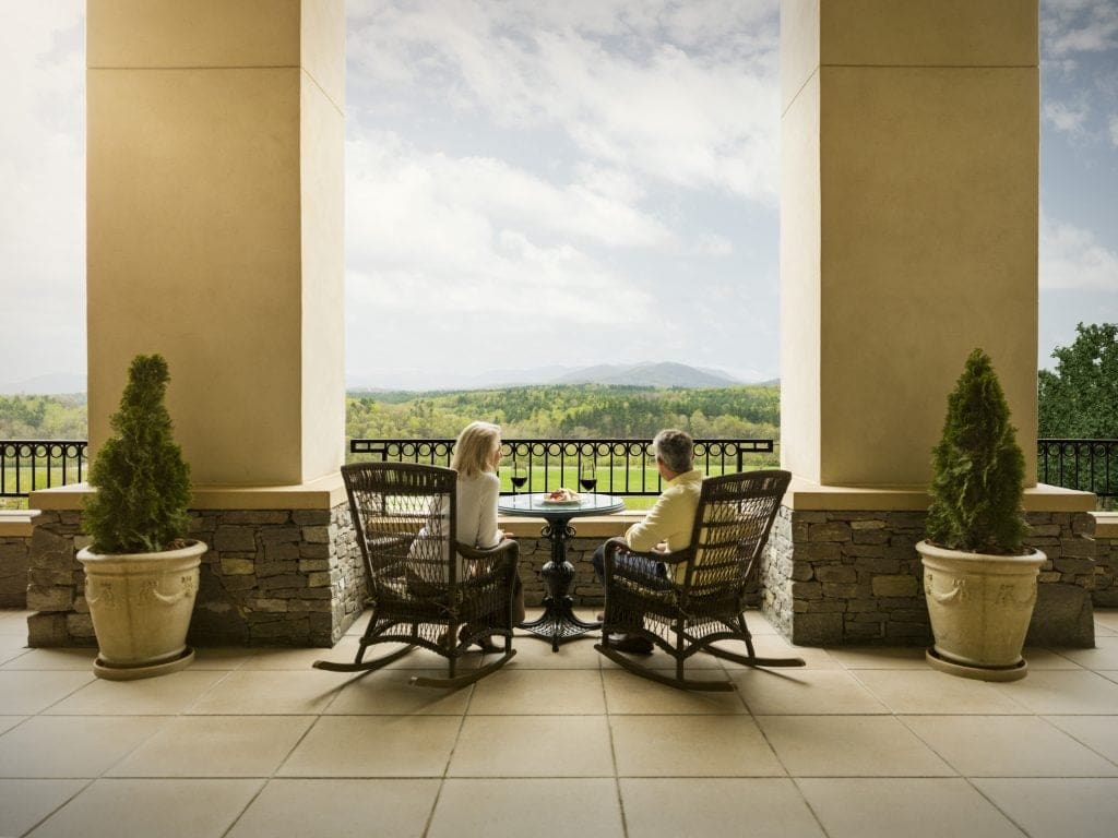 Two people enjoy a glass of wine on the veranda of The Inn on Biltmore Estate.