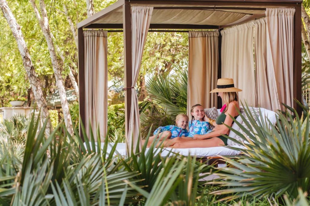 A mom and her two kids sit together in a cabana at Las Colinas Resort, one of the best hotels in Dallas for families.