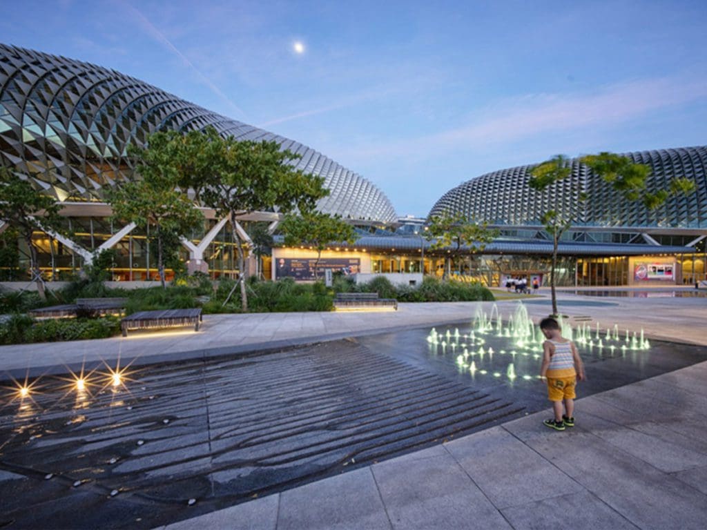 A young boy walks around a plaza with a water feature while on a Esplanade Tour in Singapore.
