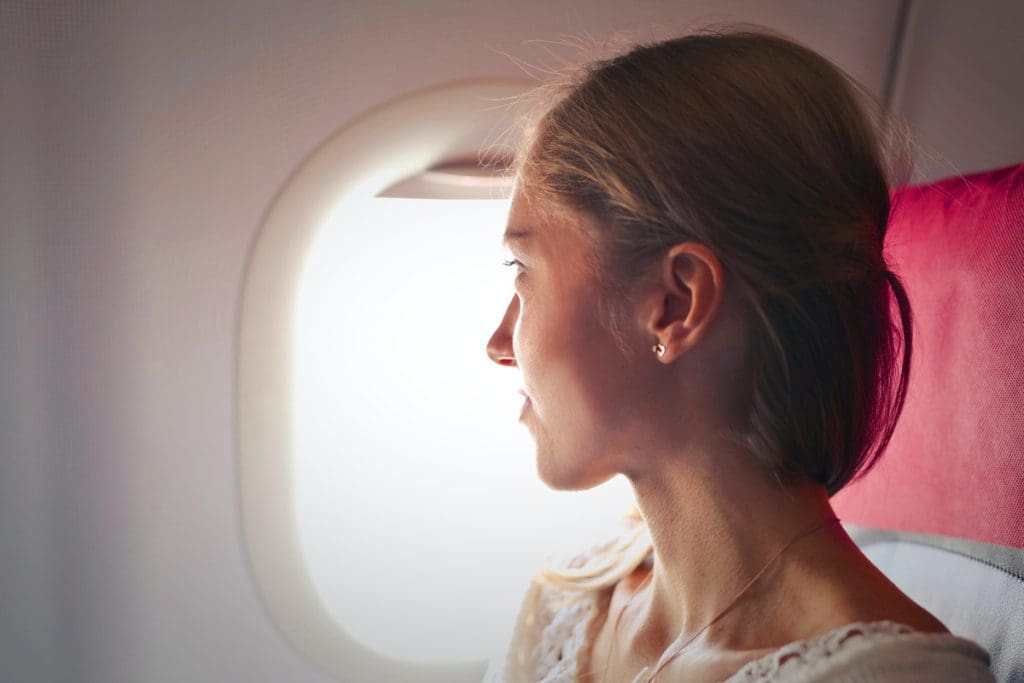A woman looks out the plane window during her flight.