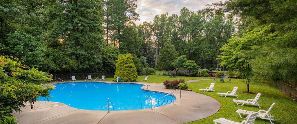 The outdoor pool surrounded by lush greenery at Photo Courtesy: Highland Lake Inn & Resort – Flat Rock, one of the best hotels in Asheville for families.