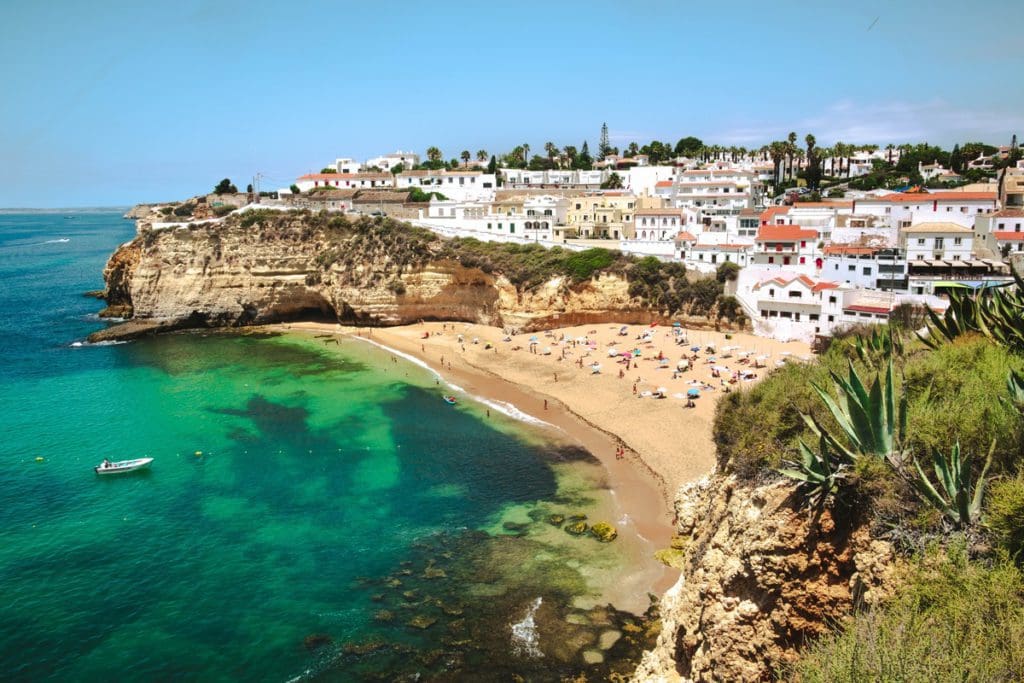 A view of a beach below a historic old town in the Algarve region of Portugal.