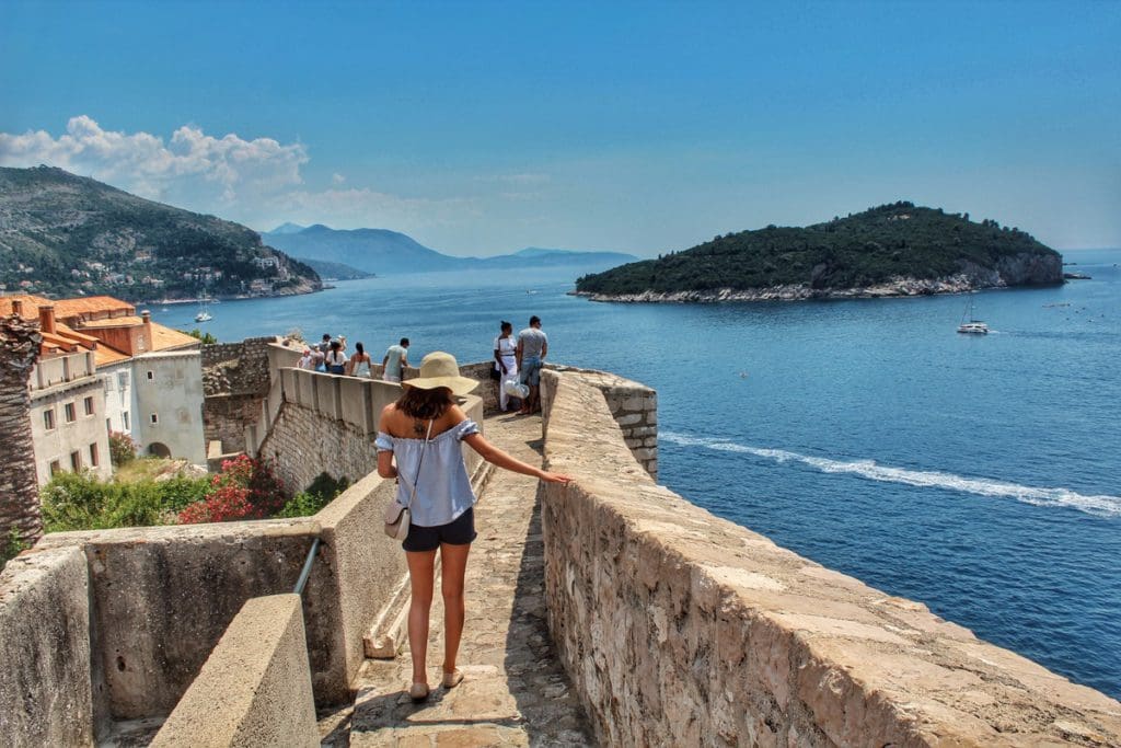 Several people walk along the Old Town Wall of Dubrovnik, Croatia.
