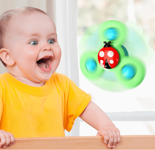 A baby watches a ALASOU spinner toy stuck on a window.
