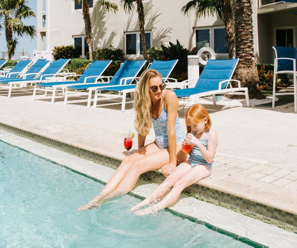 A mother and her daughter enjoy a class of tropic juice poolside at Edgewater Beach Hotel, one of the best hotels in Naples for families.