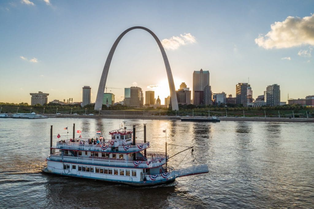 A river boat cruises down the Missouri River past downtown St. Louis and the Gateway Arch.
