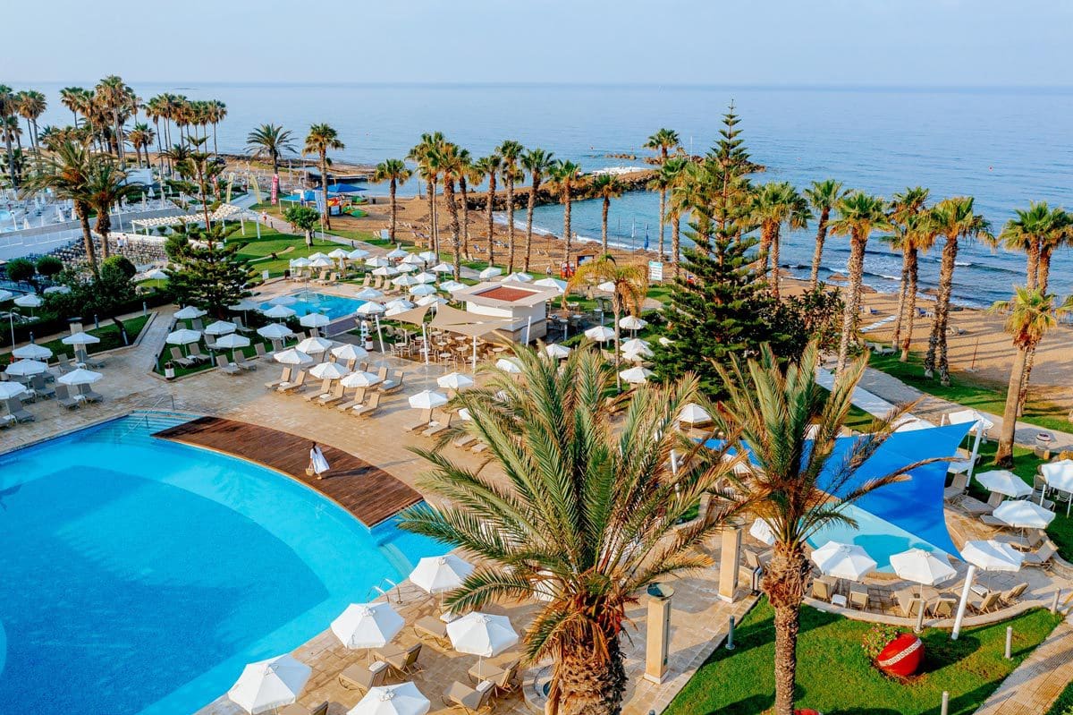 An aerial view of the pool and surrounding pool deck under palm trees at Louis Ledra Beach.