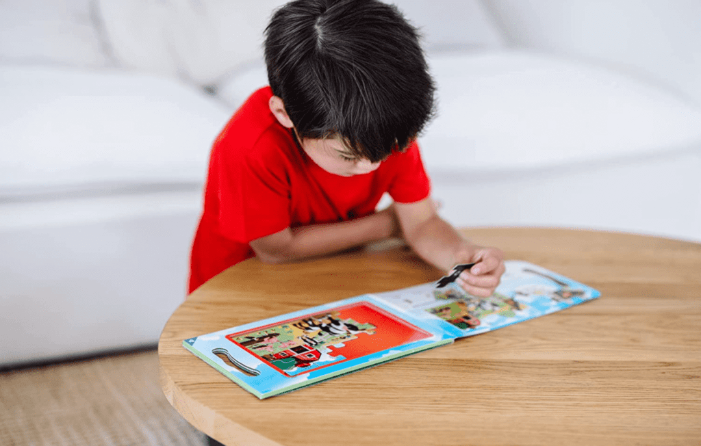 A young boy plays with a Melissa & Doug Take-Along magnetic jigsaw puzzle, one of the best travel toys for young kids.