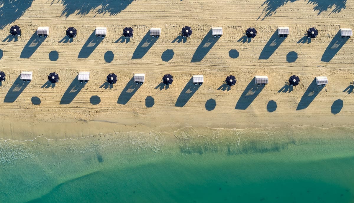 An aerial view of rows of cabanas and umbrellas on the beach at Naples Grande Beach Resort, one of the best hotels in Naples for families.