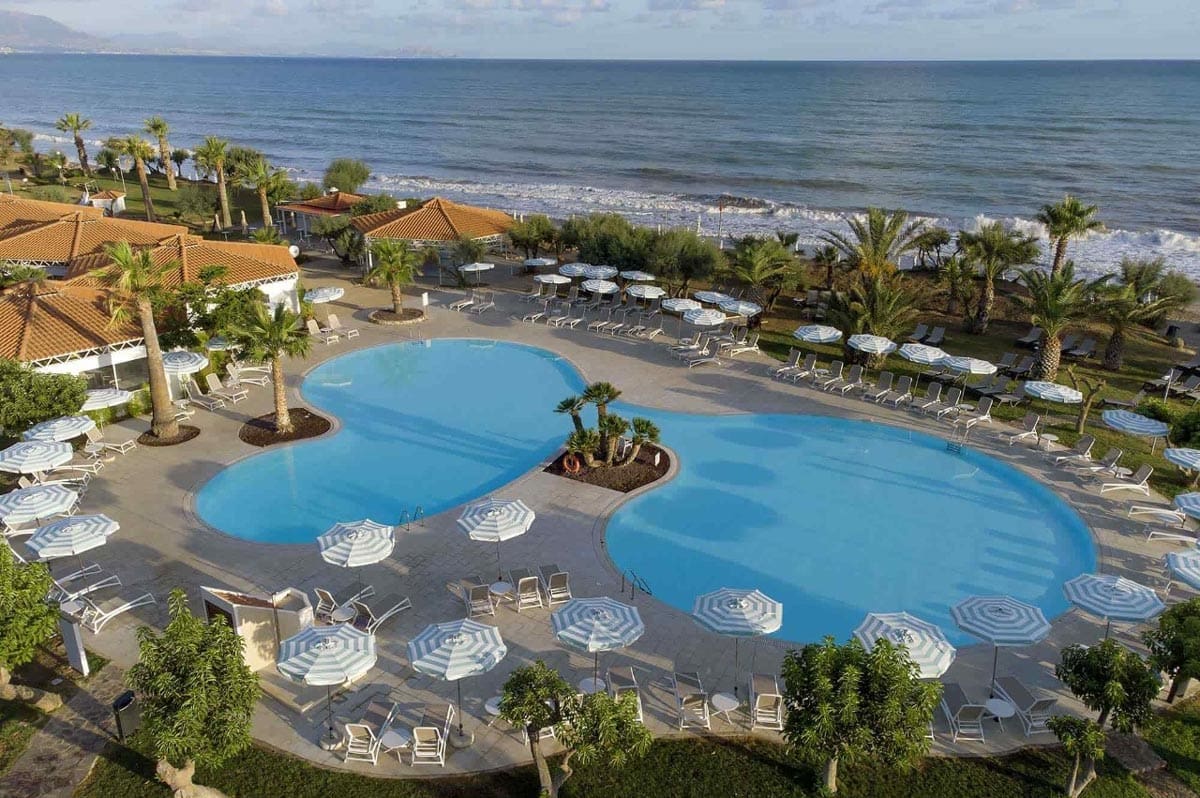 An aerial view of the outdoor, beachside pool and surrounding poolside loungers at The Grand Palladium Sicilia Resort & Spa.