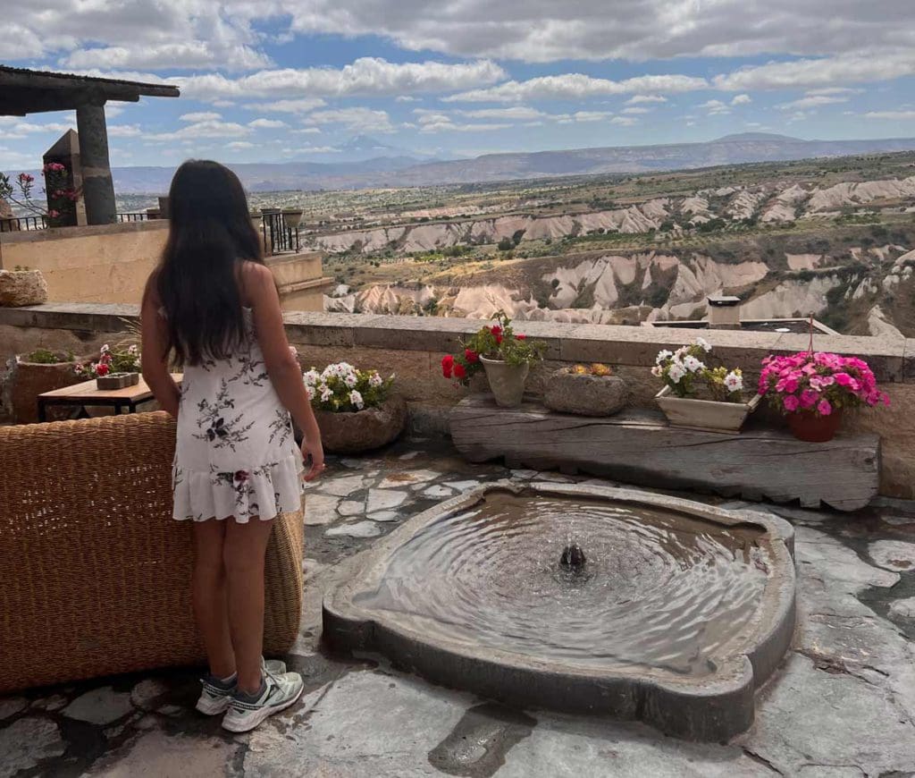 A young girl looks out onto a view of Cappadocia from her hotel.
