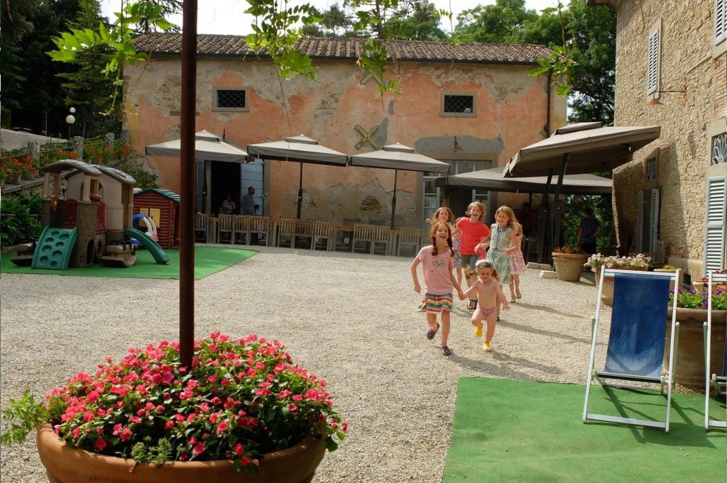 A family runs through the courtyard of Villa Pia, one of the best all-inclusive resorts In Italy for families.