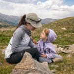 A mom and her young daughter enjoy a trail snack, while hiking in Denver.