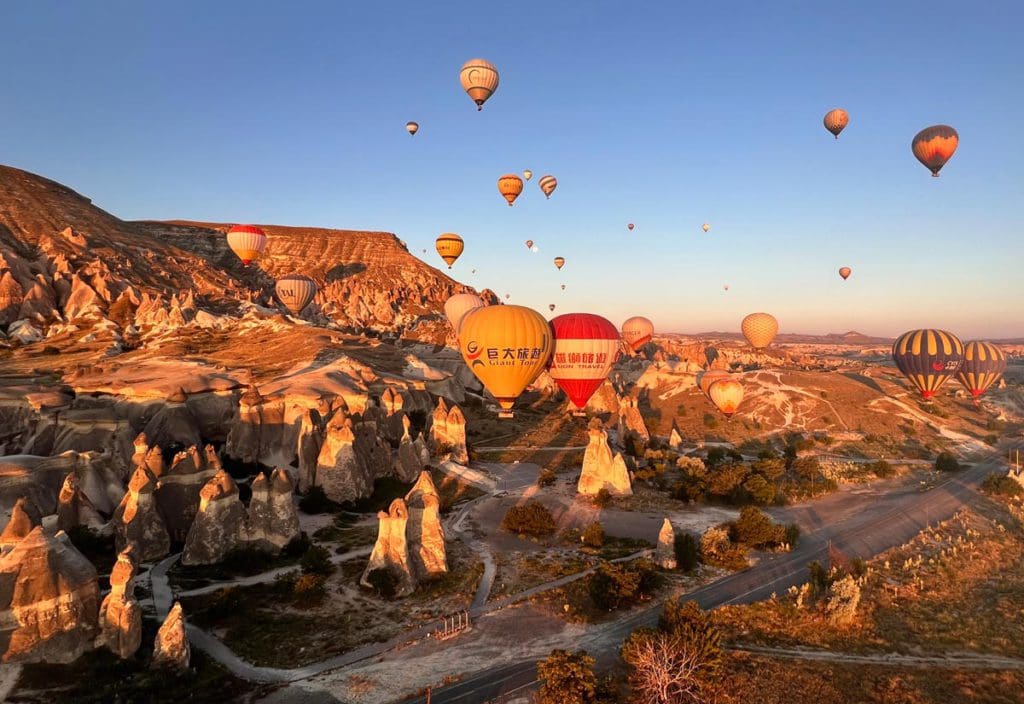 Several hot air balloons float over Cappadocia at sunrise, a must-do activity on a Turkey itinerary for families.
