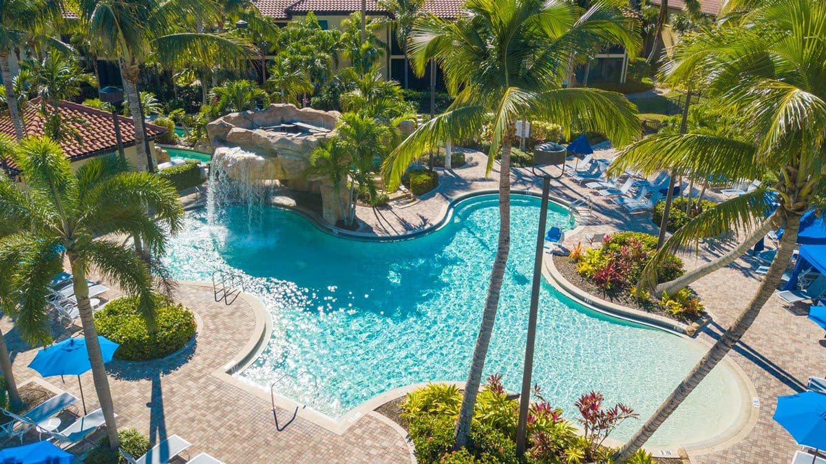 An aerial view of the pool and surrounding palm trees at Naples Bay Resort & Marina, one of the best hotels in Naples for families.