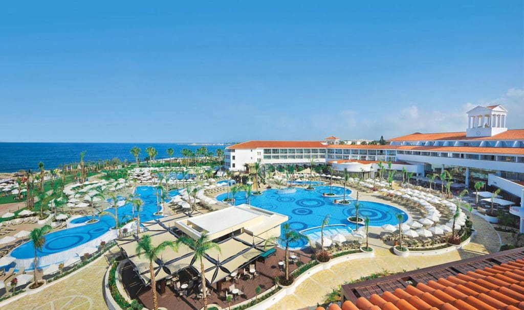 An aerial view of the pool and surrounding resort buildings and features at Olympic Lagoon Resorts, Paphos, one of the best all-inclusive resorts in Cyprus for families.