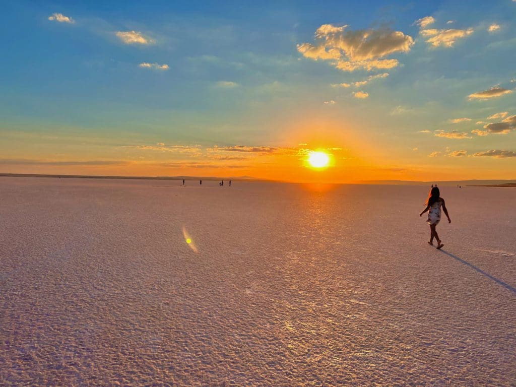 A young girl walks across the pink salt flats of Tuz Gölü at sunrise, a must on a Turkey itinerary for families.