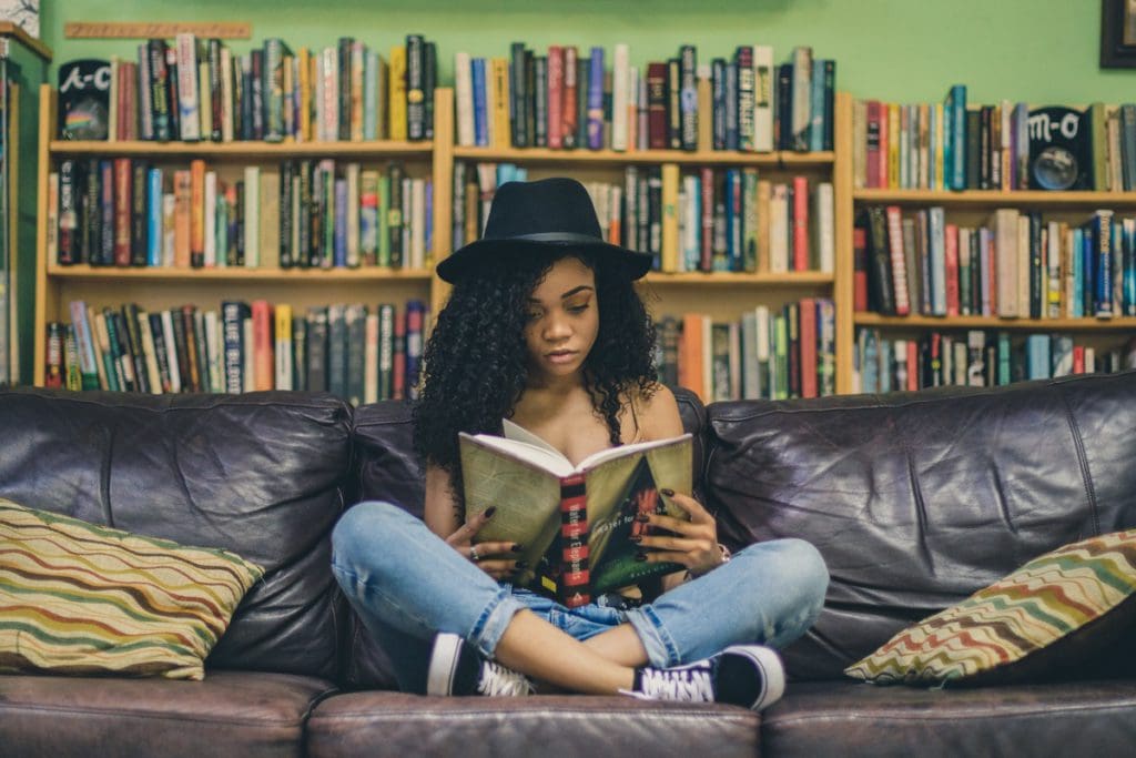A teen girl reads a book in the middle of a bookstore.