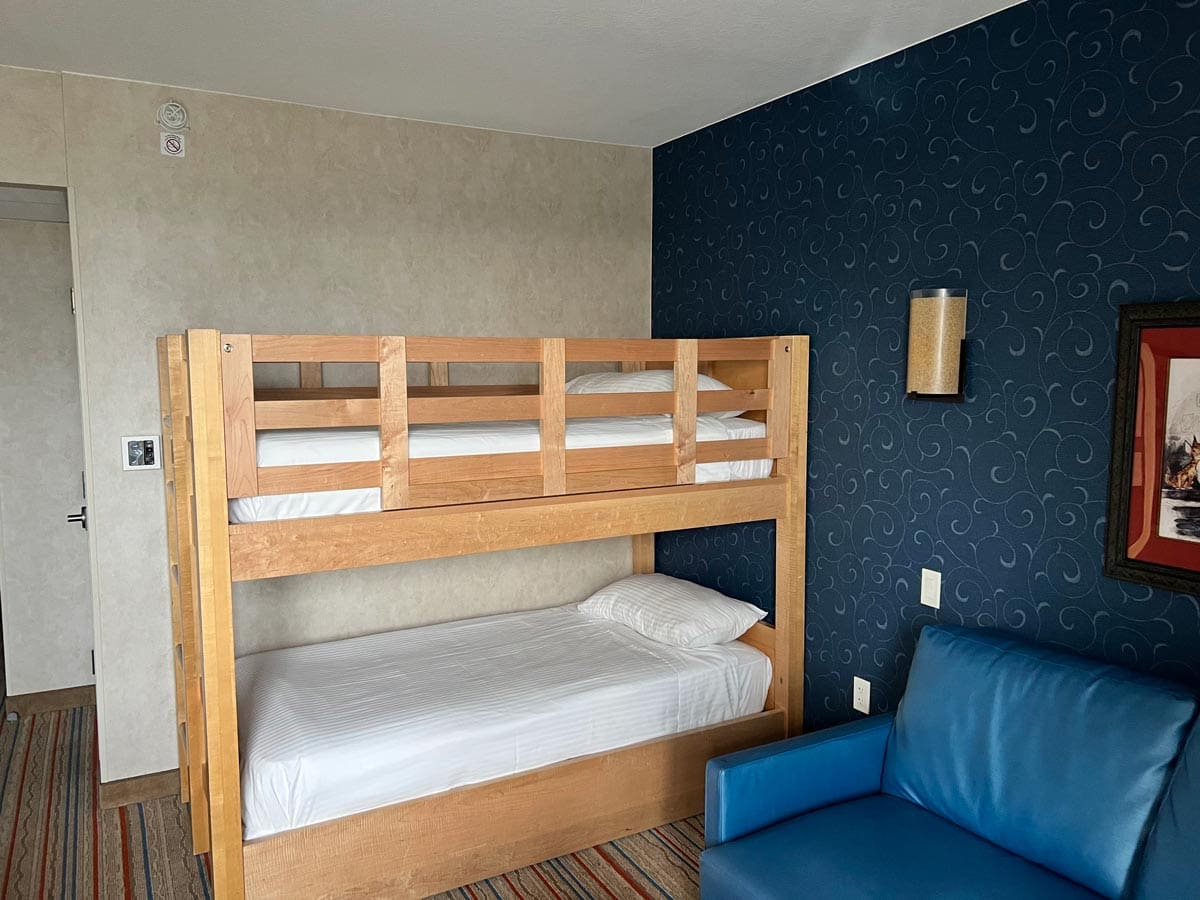Inside one of the bunkbed family rooms at Howard Johnson by Wyndham Anaheim Hotel & Water Playground, featuring a bunkbed and chair.