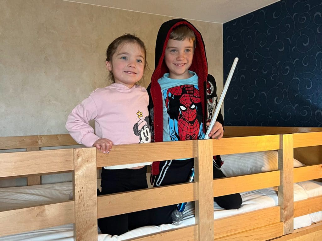 Two kids sit together on the top bunk within their family room at Howard Johnson Anaheim. 