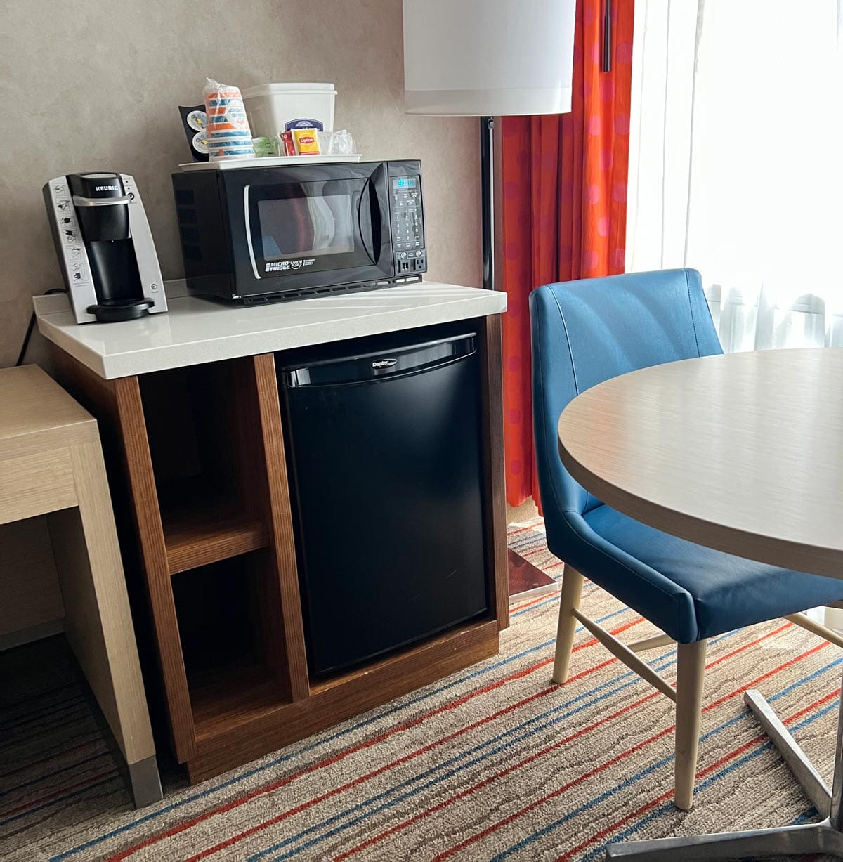 Inside a room at Howard Johnson Anaheim, featuring a small table and in-room mini fridge.