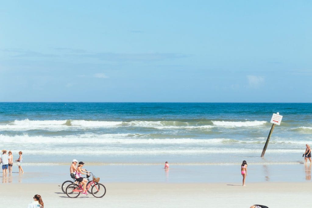 A couple riding bikes along the Daytona Beach shore.