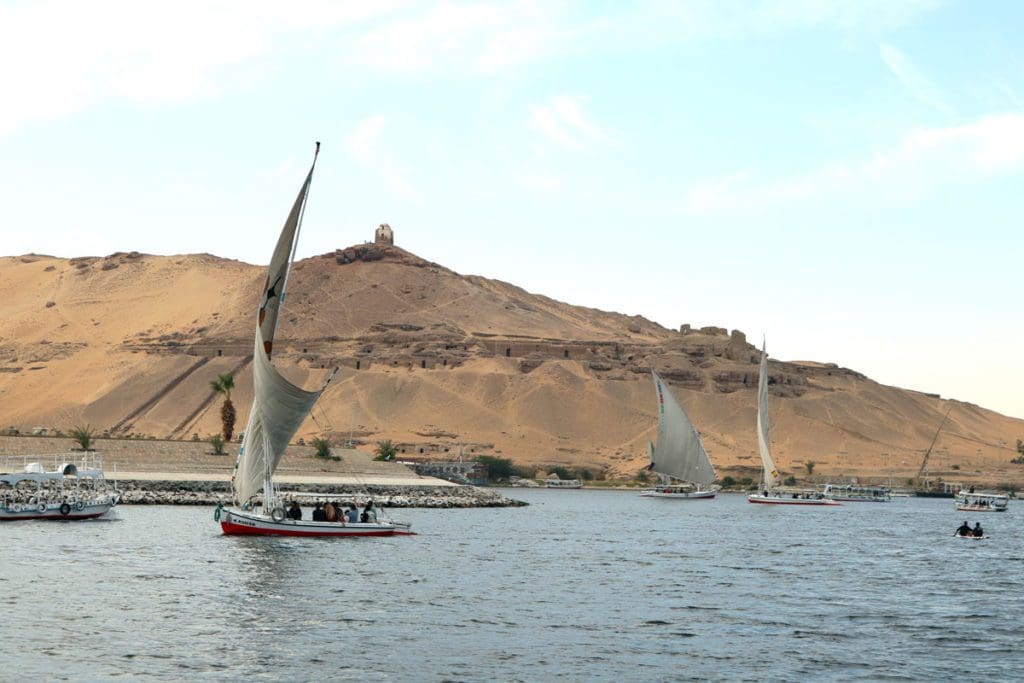 Several small boats navigate the Aswan River in Egypt.