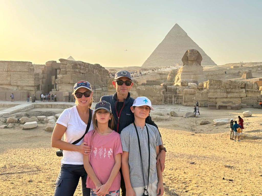 A family of four poses together, with the Sphynx in the background, while visiting Egypt with kids.
