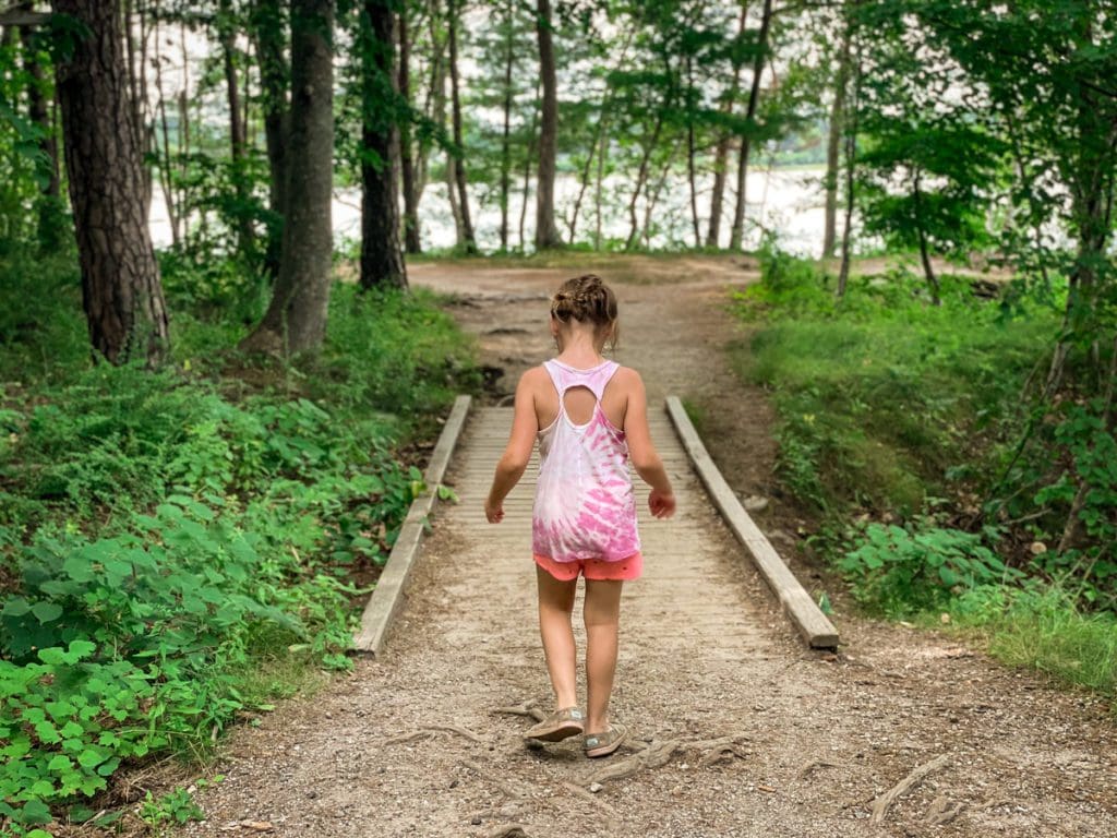 A young girl walks down a lush trail in Mackworth Island State Park, near Portland, Maine.