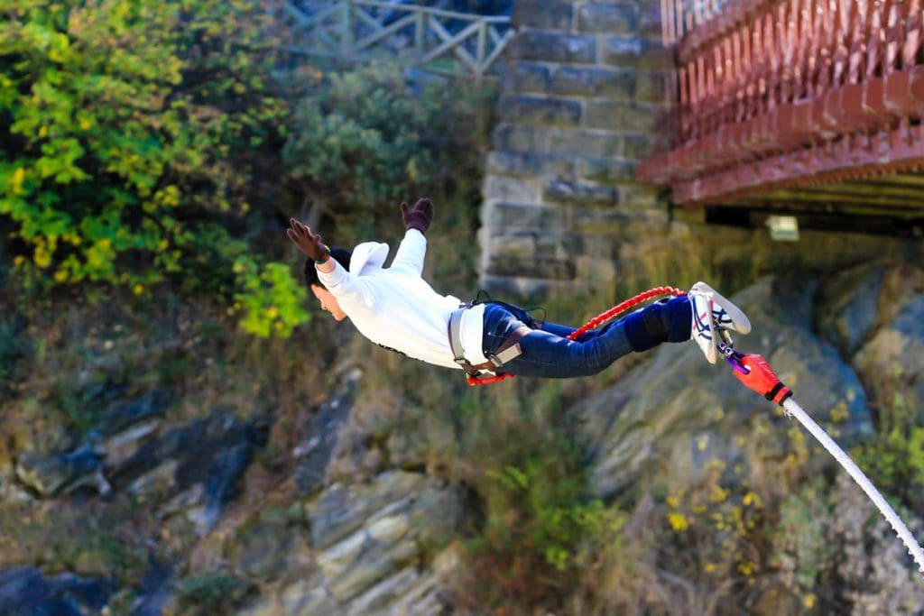 A teen bungee jumps from a bridge, one of the best extreme sports to do with teens on a family trip.