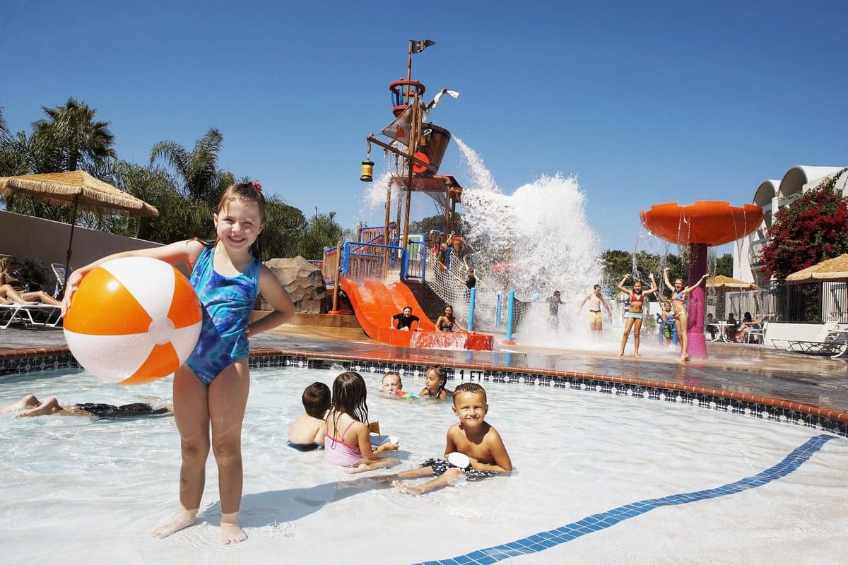 Sever kids play at the outdoor water playground on a sunny day at Howard Johnson Anaheim.