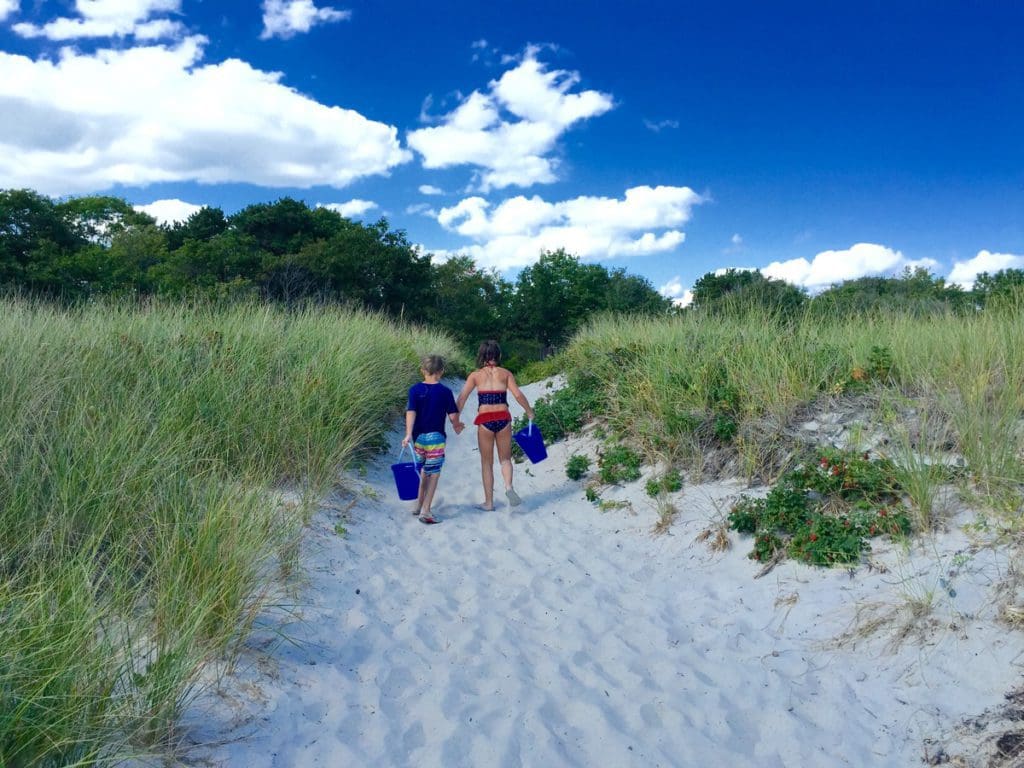 Two kids walk down a sandy path toward the sea at Inn by the Sea.