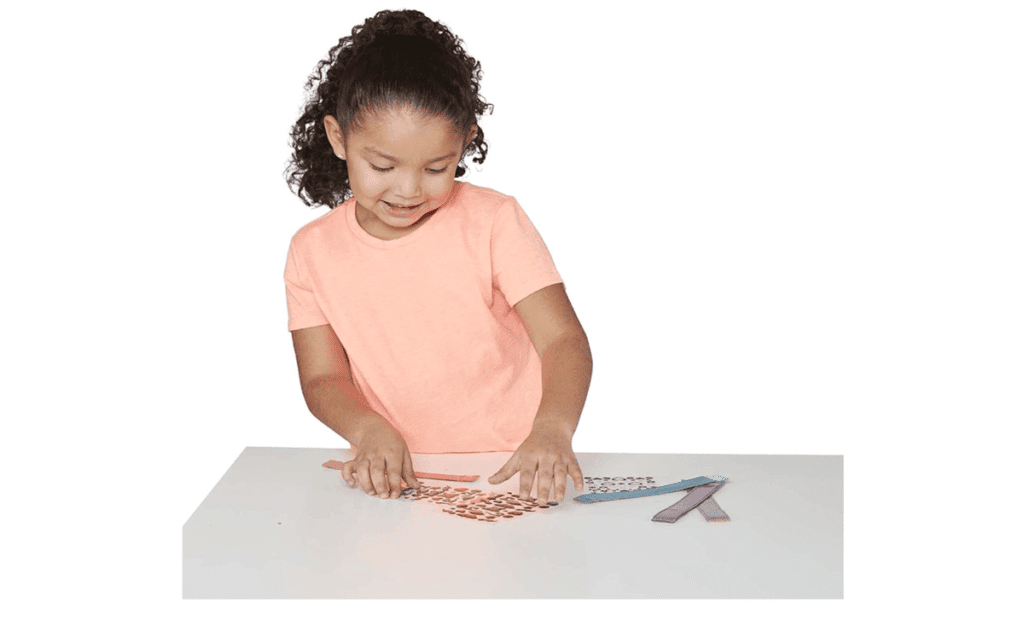 A product shot of a young girl playing with the Melissa & Doug Design-Your-Own Bracelets Kit, one of the best travel toys for young kids.