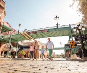 A family of four walks under the iconic sign for Centro Ybor, a historic neighborhood in Tampa Bay.