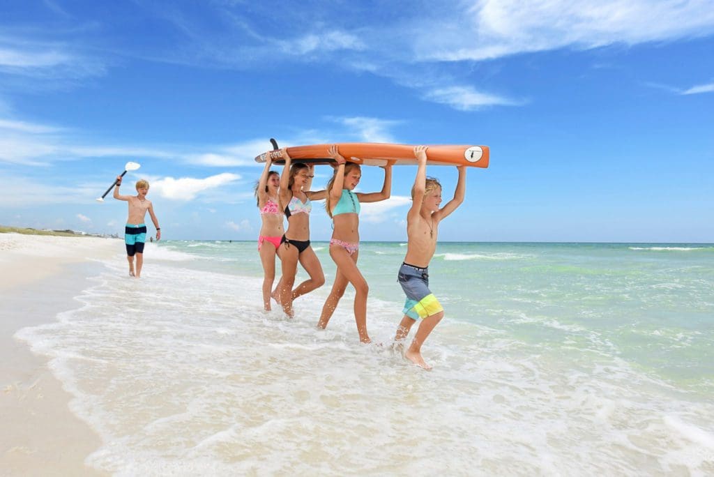 Group of teenage friends holding surfboard along the shoreline of Grayton Beach State Park in Santa Rosa Beach, one of the best Florida beaches for families.