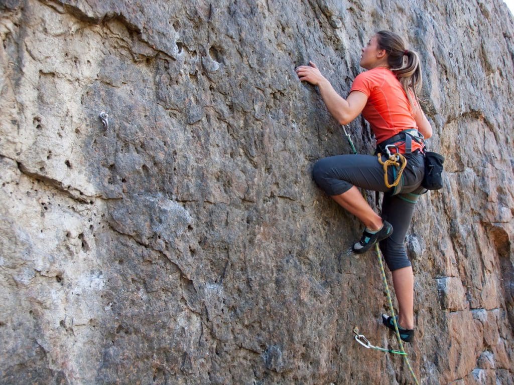 A teen girl rock climbs on a family vacation.