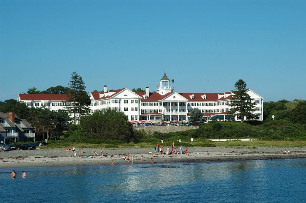 People explore the beach of the The Colony Hotel, with resort buildings in the background.