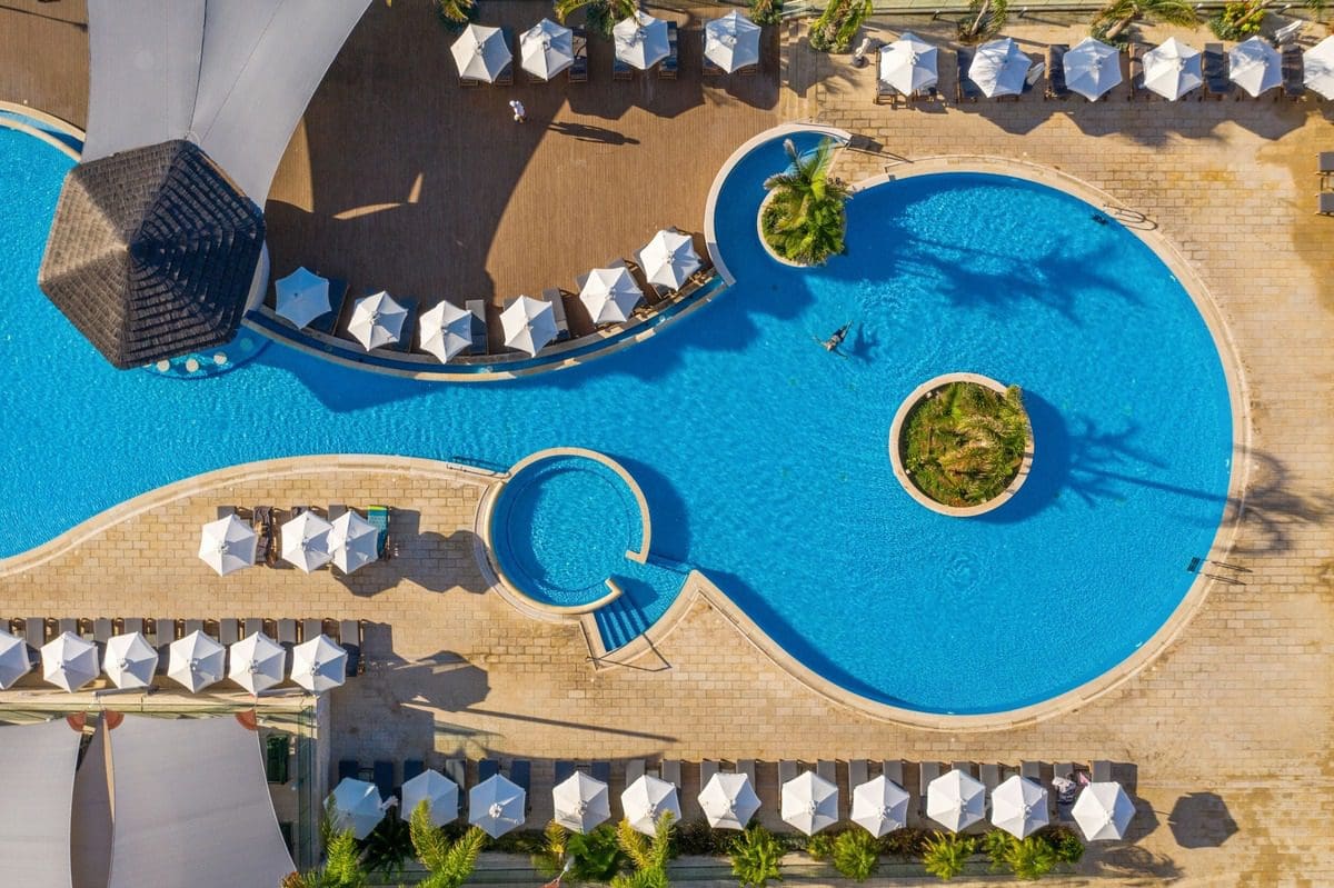 An aerial view of the pool and surrounding cabanas at The Royal Apollonia, one of the best all-inclusive resorts in Cyprus for families.