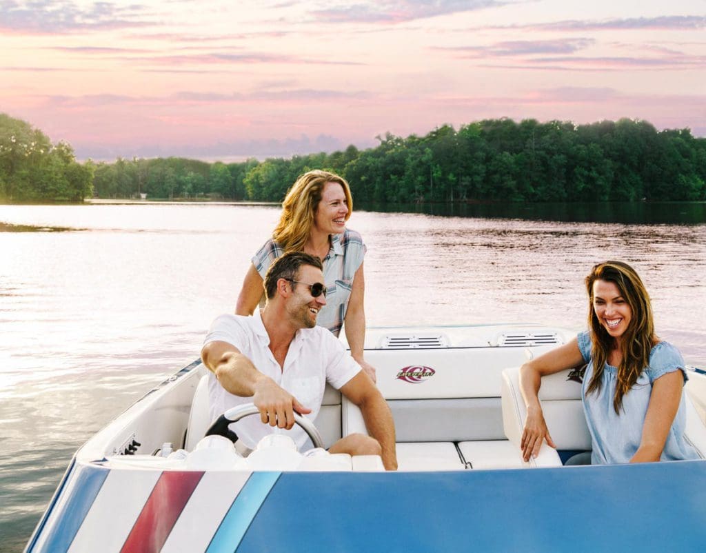 Three people talk in the back of a boat, while cruising the waters of High Rock Lake.